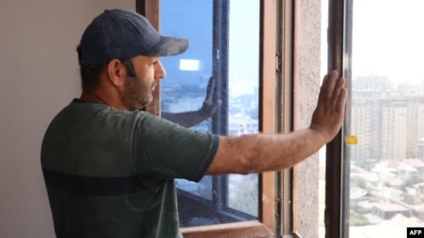 Tajik co<em></em>nstruction worker Zoir Kurbanov looks out from a window as he renovates a new apartment in Dushanbe on Sept. 17, 2023.