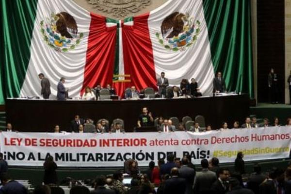 álvarez Máynez speaks in Co<em></em>ngress while deputies display banner against the Internal Security Law, in November 2017.